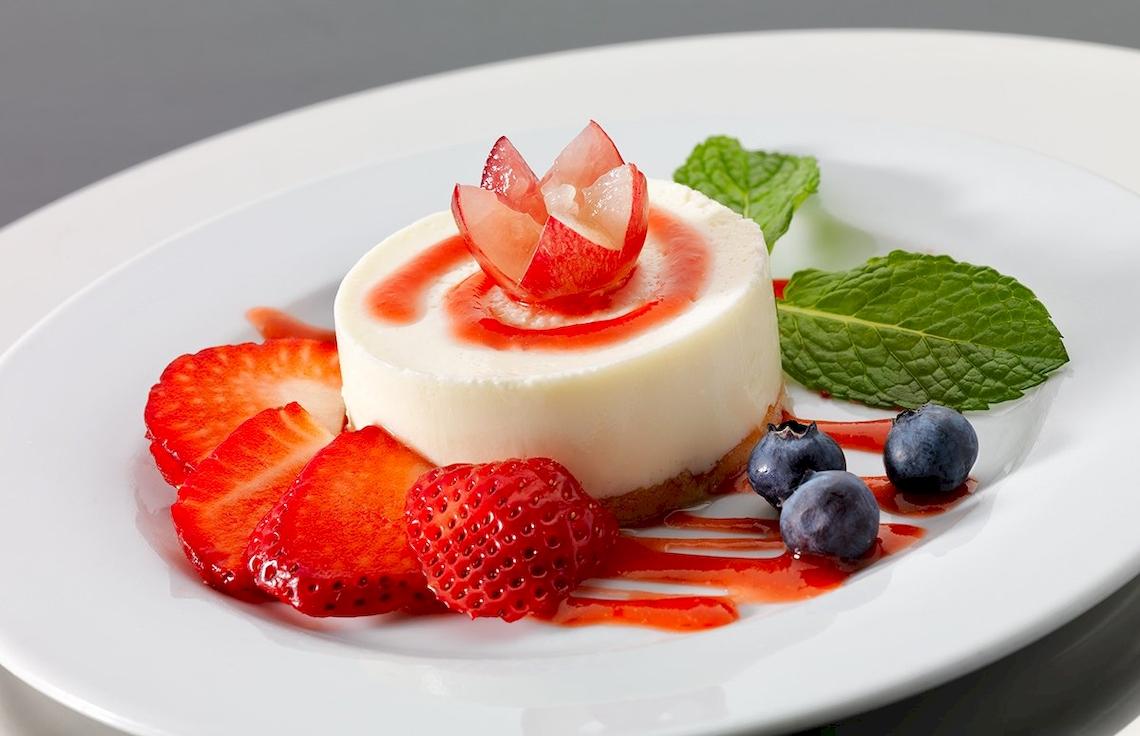 Dessert im H10 Estepona Palace Hotel mit Käsekuchen, Früchten und Minzblättern.