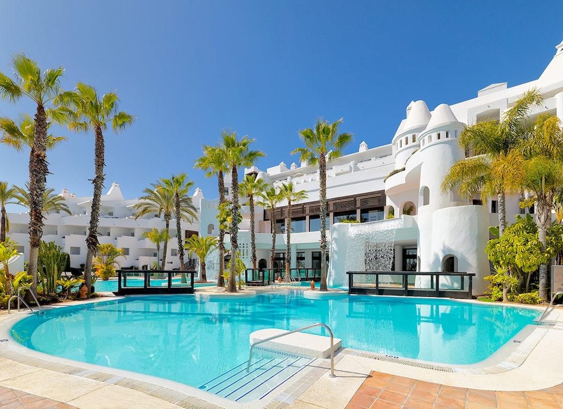 Außenbereich des H10 Estepona Palace Hotels mit Swimmingpool und Palmen.