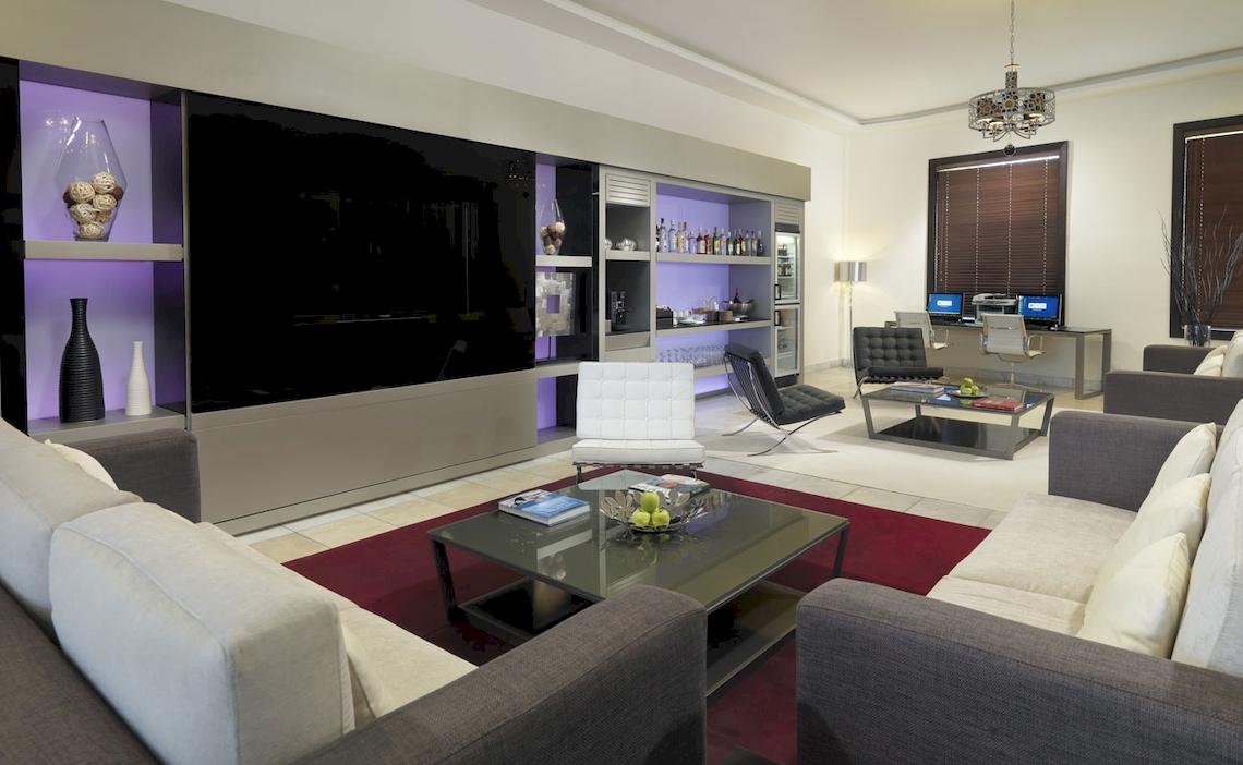 Modernes Wohnzimmer im H10 Estepona Palast mit großen Sofas, Tisch, Fernseher und Dekor.