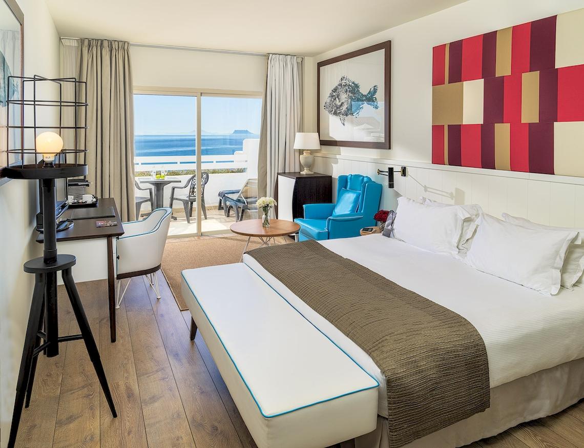 Innenansicht eines Hotelzimmers im H10 Estepona Palace mit Blick auf das Meer und eine Terrasse.