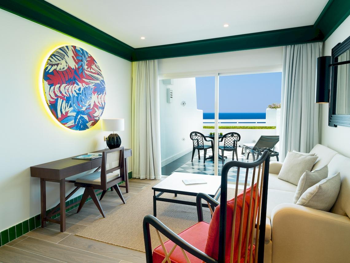 Wohnzimmer des H10 Estepona Palace mit Blick auf das Meer und modernen Möbeln.