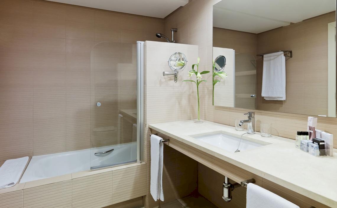 Badezimmer im H10 Estepona Palace mit Badewanne, Waschbecken und Spiegeln.