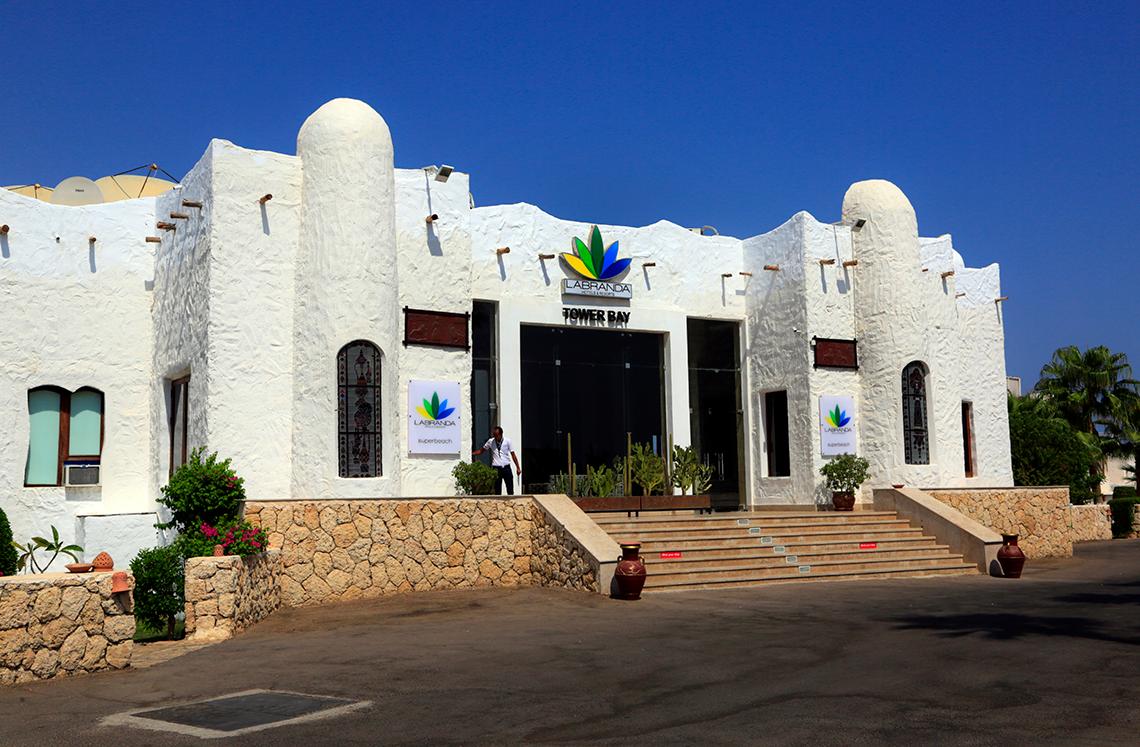 Eingang des Sharm Club Beach Resorts mit einer Person und Pflanzen davor