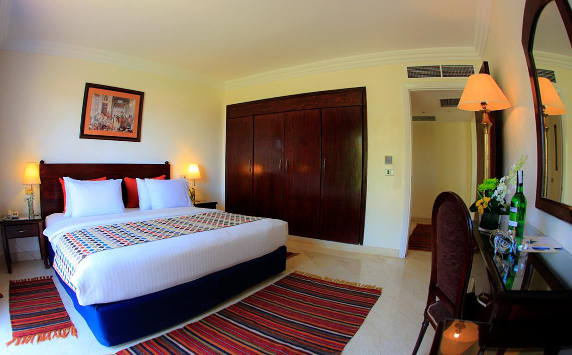 Sharm Club Beach Resort Hotelzimmer mit Bett, Teppichen und Möbeln.