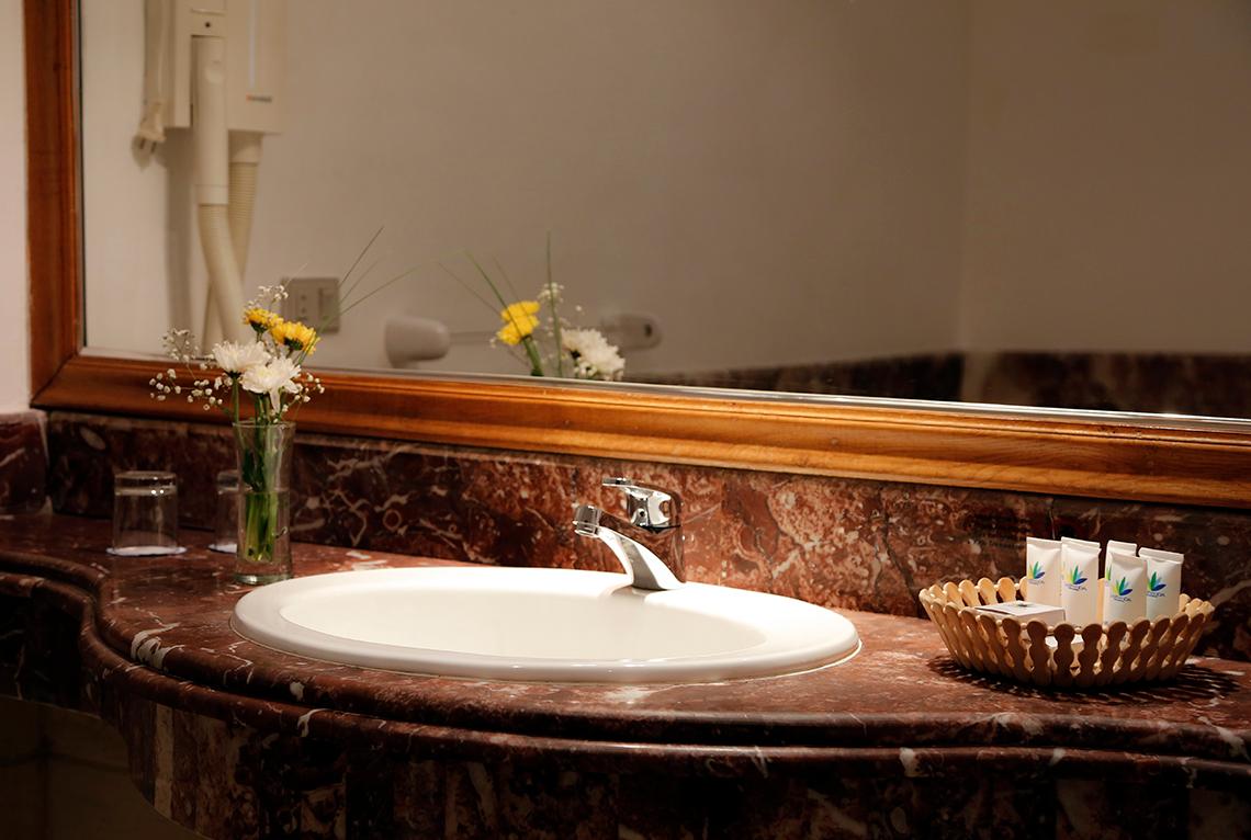 Badezimmer im Sharm Club Beach Resort mit einem Waschbecken, Spiegel und Blumen