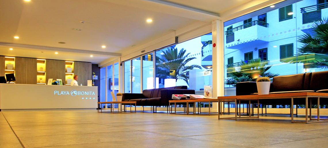 Lobby des Hotels Servatur Playa Bonita mit Empfang, Sitzgelegenheiten und Palmen