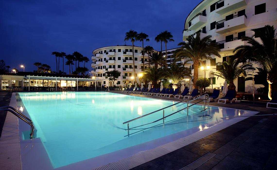Poolbereich des Servatur Playa Bonita Hotels bei Abendbeleuchtung mit Palmen und Loungechairs