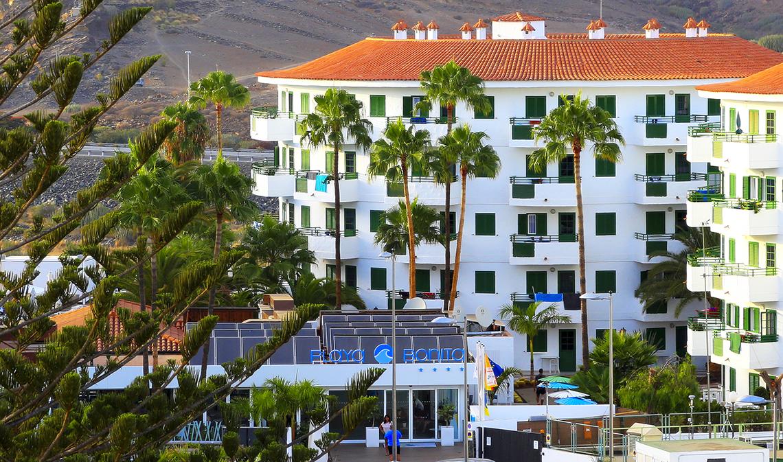 Blick auf das Servatur Playa Bonita Hotel mit Palmen und orangefarbenem Dach