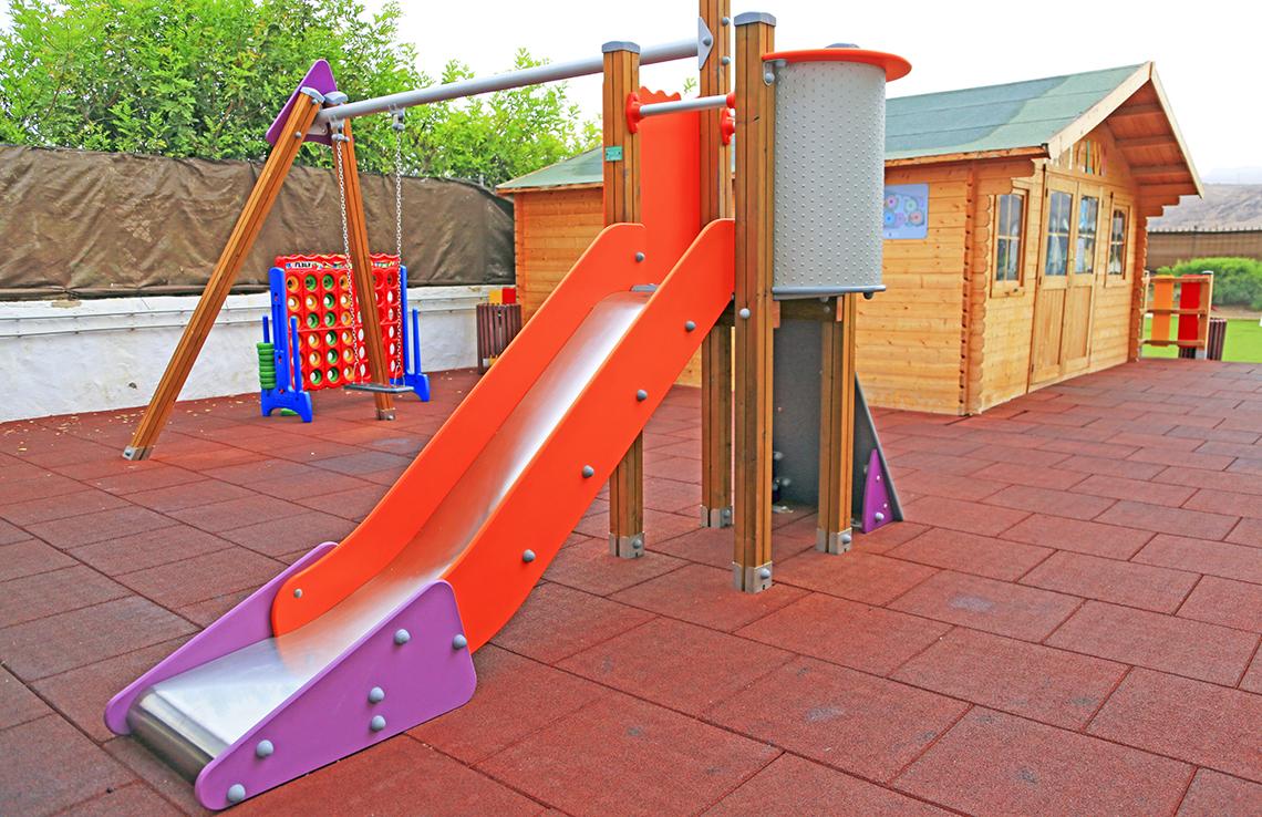 Buntes Spielgerüst mit Rutsche und Schaukeln auf einer Terrasse