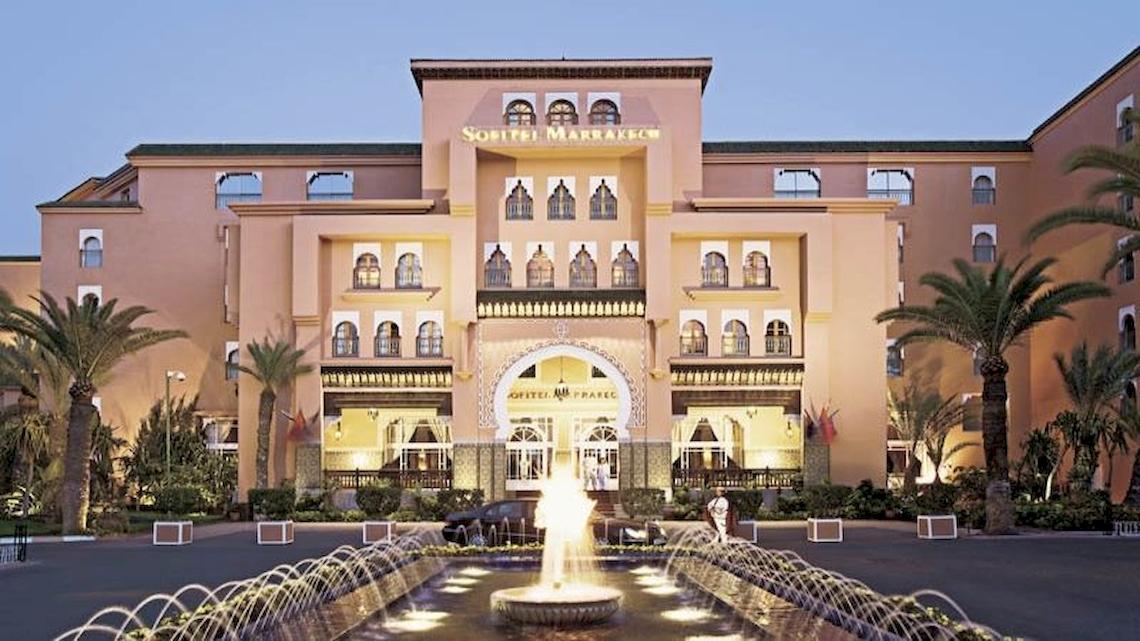 Vorderansicht des Sofitel Marrakech Lounge & Spa Hotels mit Brunnen und Palmen.