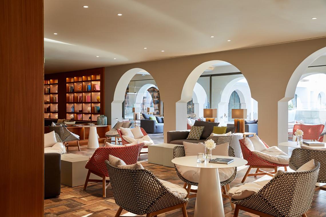 Loungebereich im MarBella Corfu Hotel mit Möbeln und Bücherregalen.