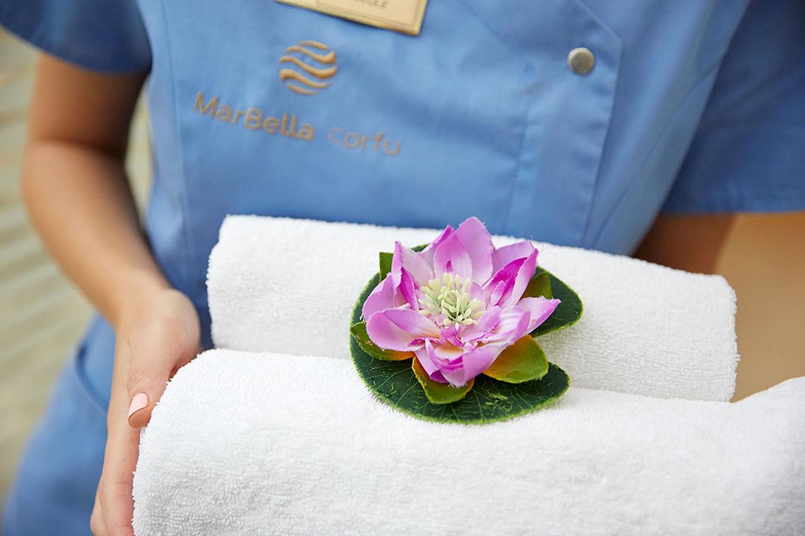 Mitarbeiterin des MarBella Corfu Hotels mit Handtüchern und Blume