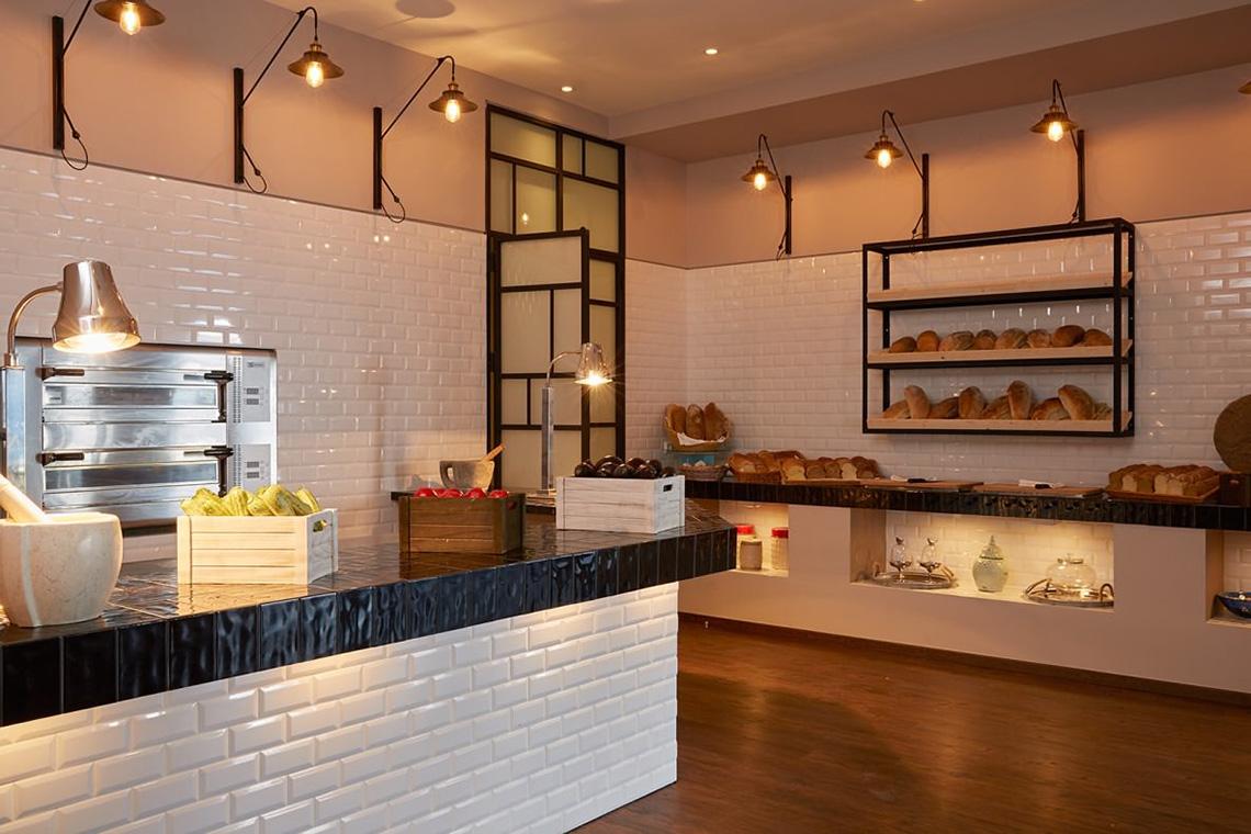 Bäckerei-Theke im MarBella Corfu mit weiß gefliester Wand und Holzboden