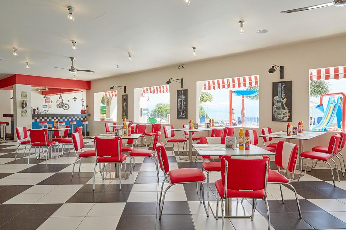 Innenansicht des MarBella Corfu Restaurants mit rot-weißem Schachbrettboden und roten Stühlen.