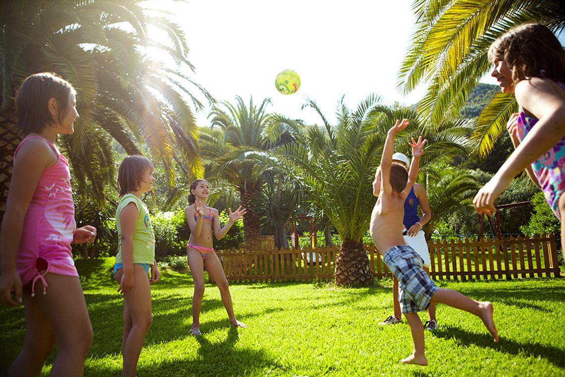 Kinder spielen im Garten des MarBella Corfu Hotels mit einem Ball.
