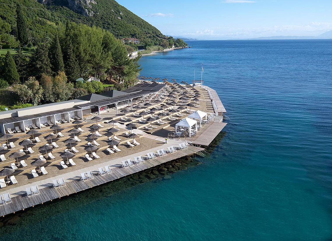 Luftaufnahme des MarBella Corfu Hotels mit vielen Liegen und Sonnenschirmen am Strand