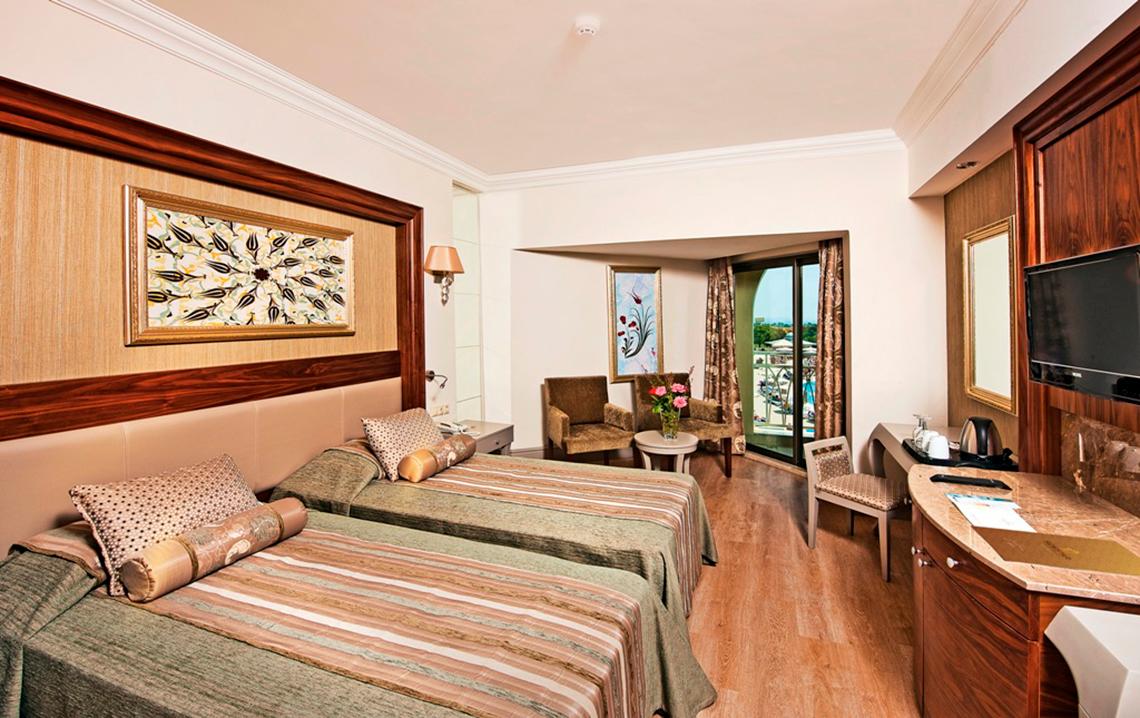 Doppelzimmer im Side Star Resort mit zwei Betten, Schränken, Fernseher und Fenster mit Balkon.