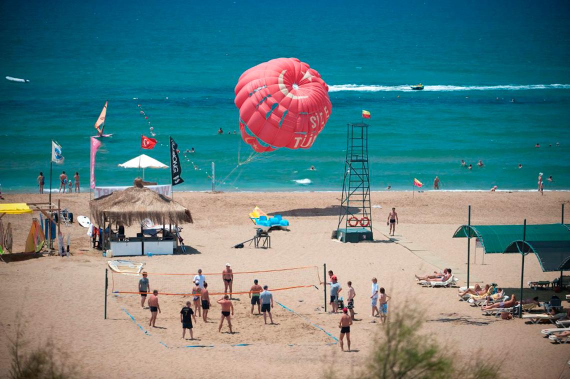 Strandszene mit Parasailing und Volleyballspiel, am Side Star Resort