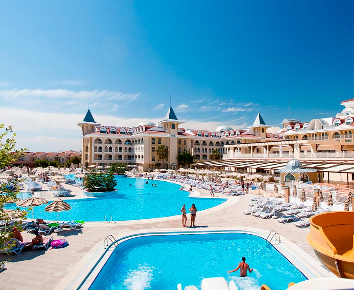 Außenansicht des Side Star Resort mit zwei Swimmingpools, Sonnenliegen und Gästen.
