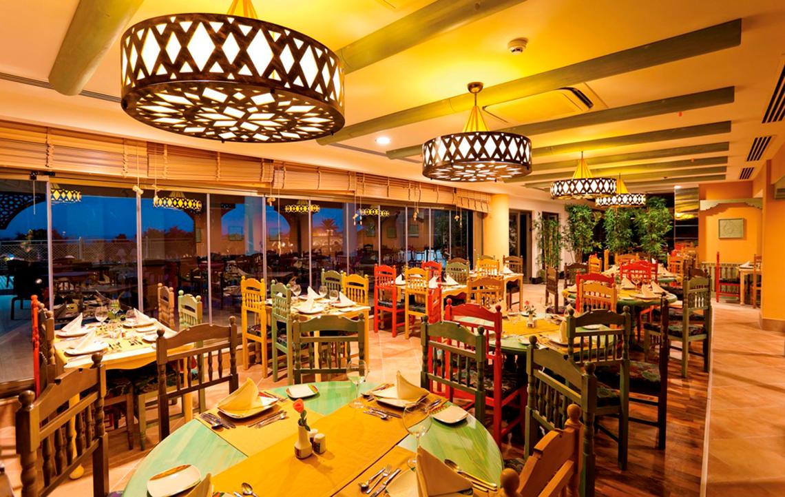 Innenbereich des Side Star Resort Restaurants mit bunten Tischen und Stühlen, großen Fenstern und dekorativen Kronleuchtern.