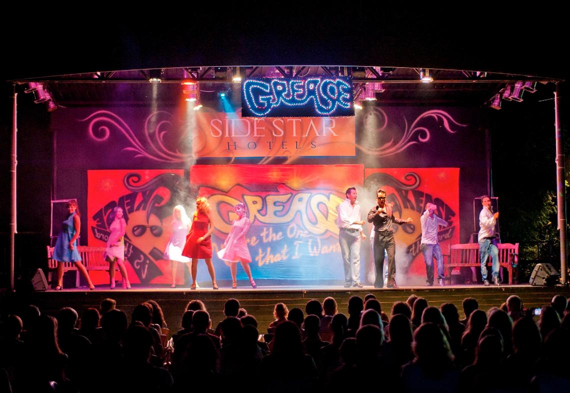 Greases Show auf der Bühne des Side Star Resort Hotels mit Darstellern und Publikum.