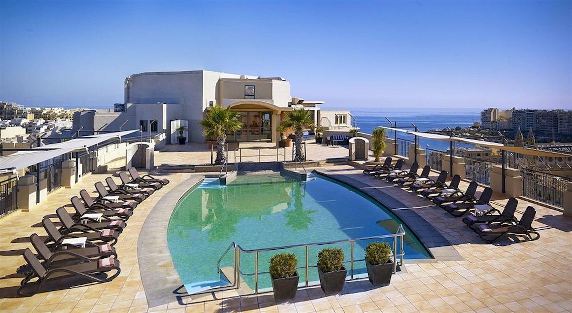 Dachterrasse mit Pool und Liegen im Malta Marriott Hotel & Spa mit Blick auf das Meer und die Stadt.