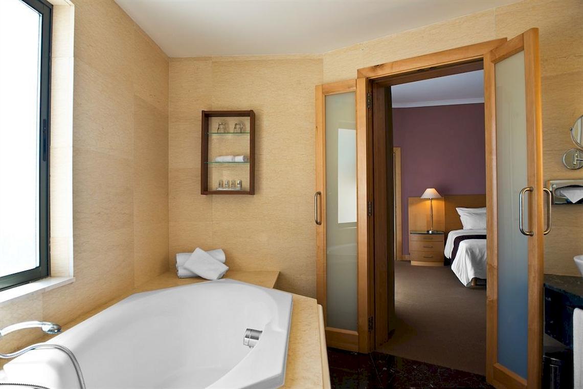 Badezimmer mit Badewanne und Bett im Malta Marriott Hotel & Spa