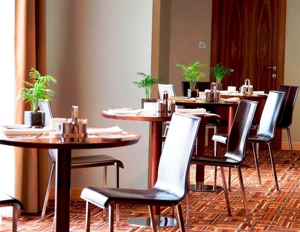 Speisesaal des Malta Marriott Hotel & Spa mit gedeckten Tischen und braunen Stühlen.