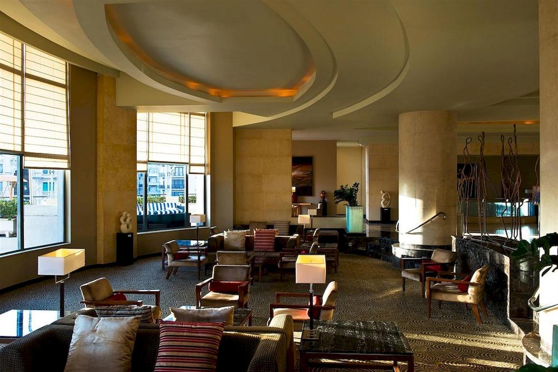 Innenansicht der Hotellobby im Malta Marriott Hotel & Spa mit modernen Möbeln und großen Fenstern.