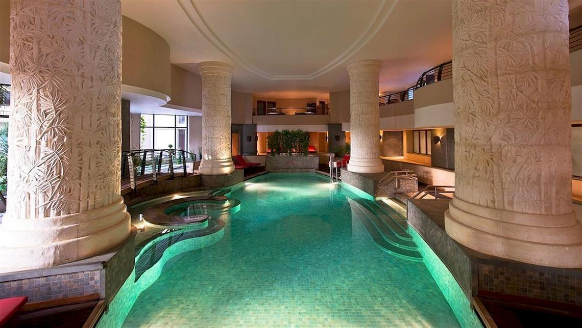 Innenpool des Malta Marriott Hotel & Spa mit großen Säulen und roten Sesseln.