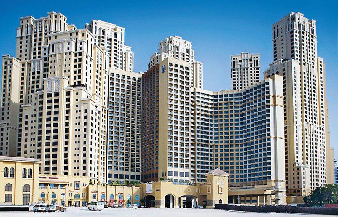 Außenansicht des Amwaj Rotana Hotels mit mehreren Gebäuden und Parkplätzen vor dem Gebäude.
