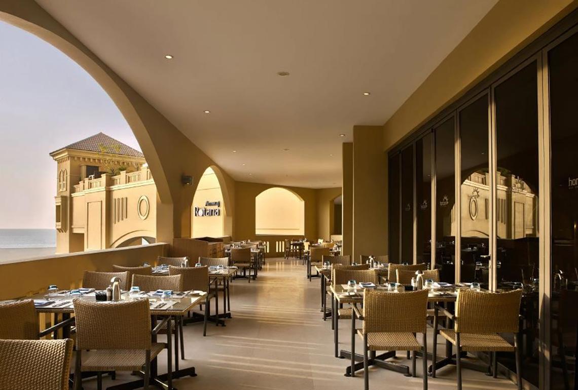 Innenansicht des Restaurants im Amwaj Rotana Hotel mit Blick auf das Meer.