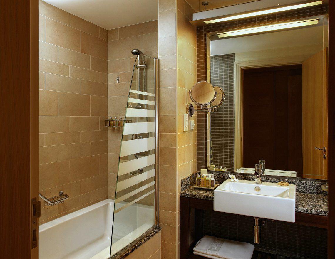 Badezimmer im Amwaj Rotana Hotel mit Badewanne, Glasdusche und Waschbecken
