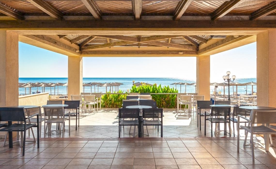 Terrasse des Blue Sea Beach Resorts mit Blick auf das Meer und Strandschirme.