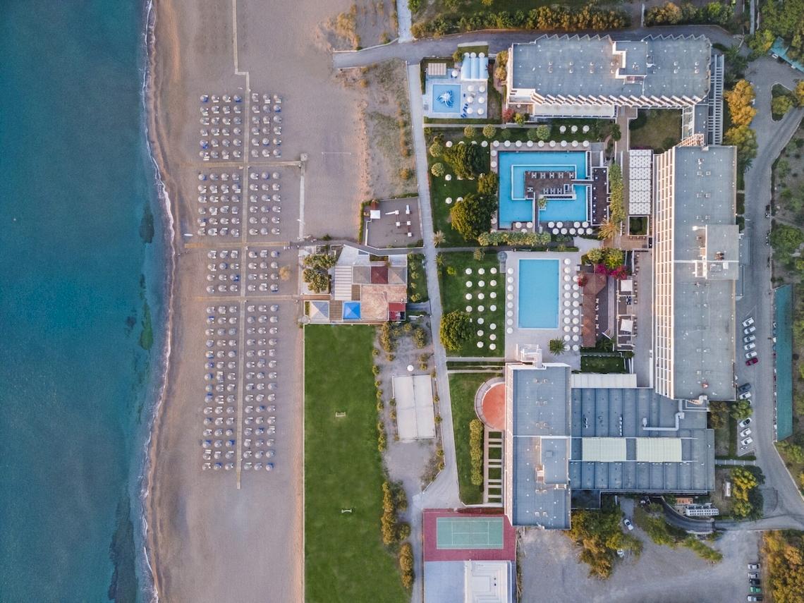 Luftaufnahme des Blue Sea Beach Resorts mit Strand, Swimmingpools und Hotelgebäuden.