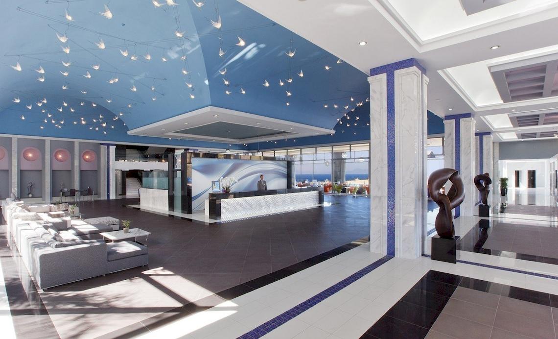 Empfangsbereich des Atrium Platinum Luxury Resort Hotel & Spa mit blauer Decke, Rezeption und Sitzmöbeln.