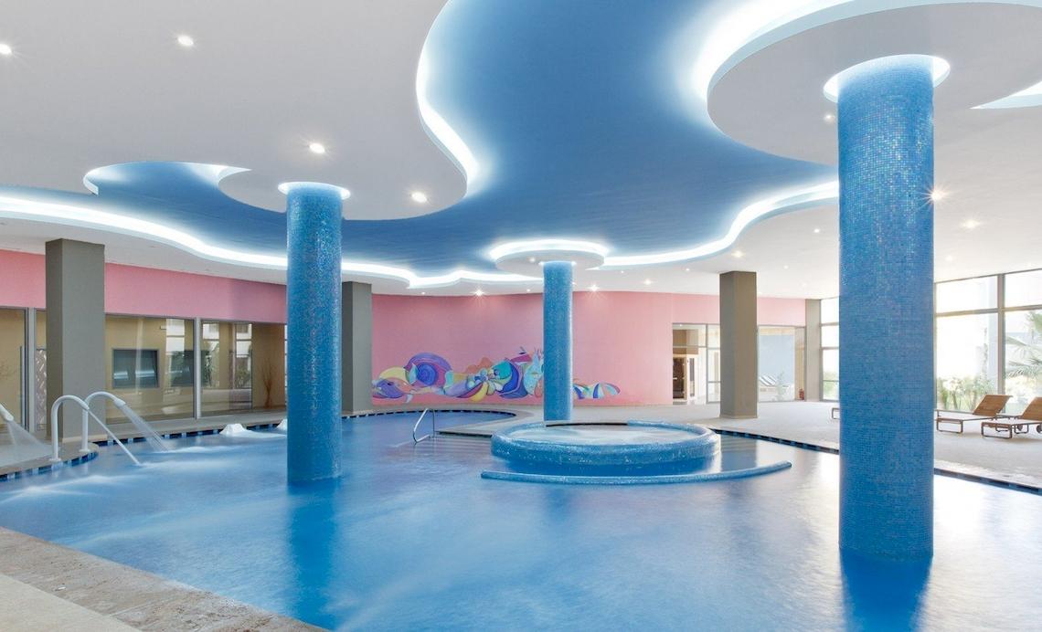 Innenpool des Atrium Platinum Luxury Resort Hotel & Spa mit blauen Säulen und bunter Wand