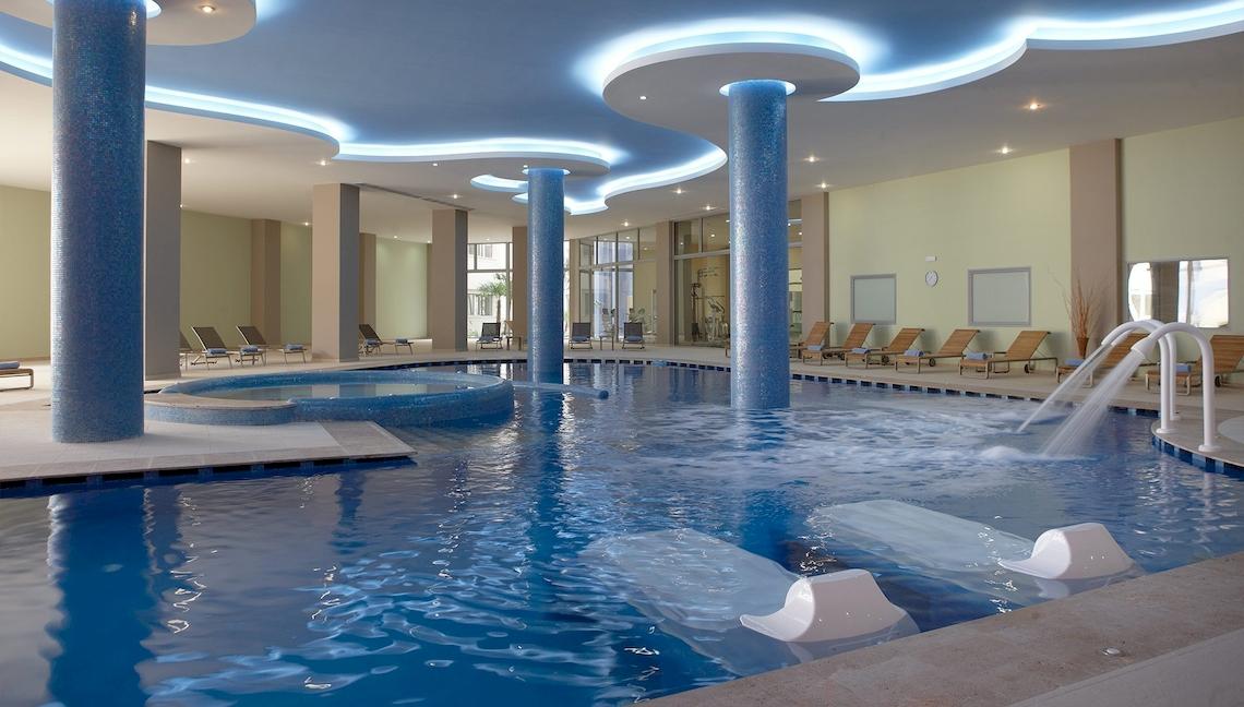 Innenpool des Atrium Platinum Luxury Resort Hotel & Spa mit blauen Säulen und Wasserfällen