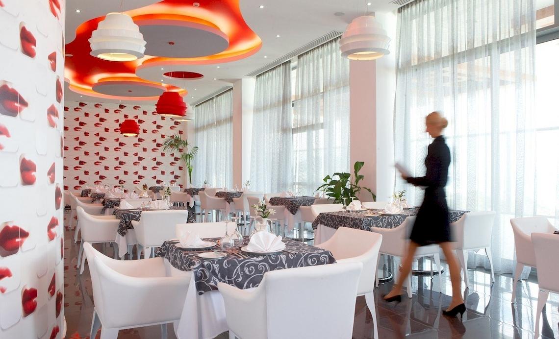 Innenraum des Atrium Platinum Luxury Resort Hotel & Spa mit roten Lippenmotiven und weißen Möbeln.