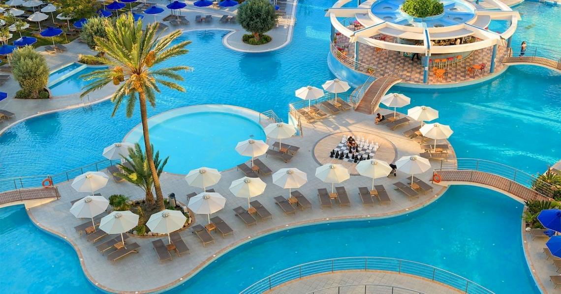 Aerial view of the Atrium Platinum Luxury Resort Hotel & Spa pool area with lounge chairs, umbrellas, and a palm tree.