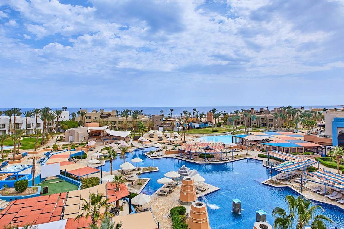 Luftaufnahme des Pick Albatros Sands Port Ghalib Resorts mit Pools, Sonnenliegen und blauem Himmel.