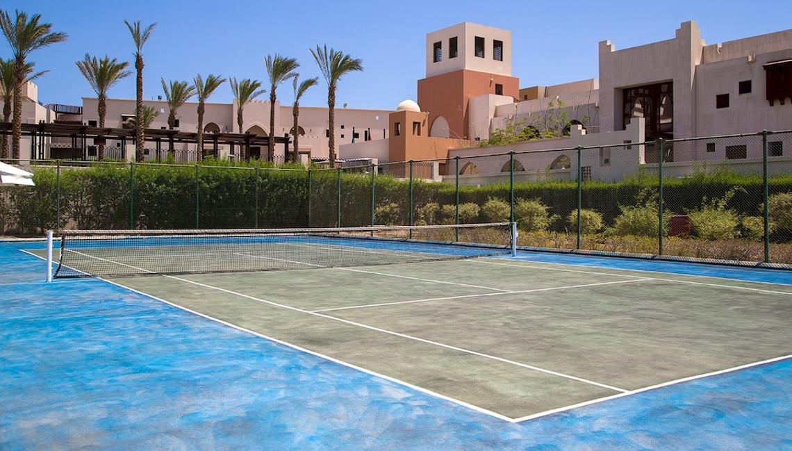Tennisplatz vor dem Hotel PickAlbatros Sands Port Ghalib mit Gebäuden im Hintergrund.
