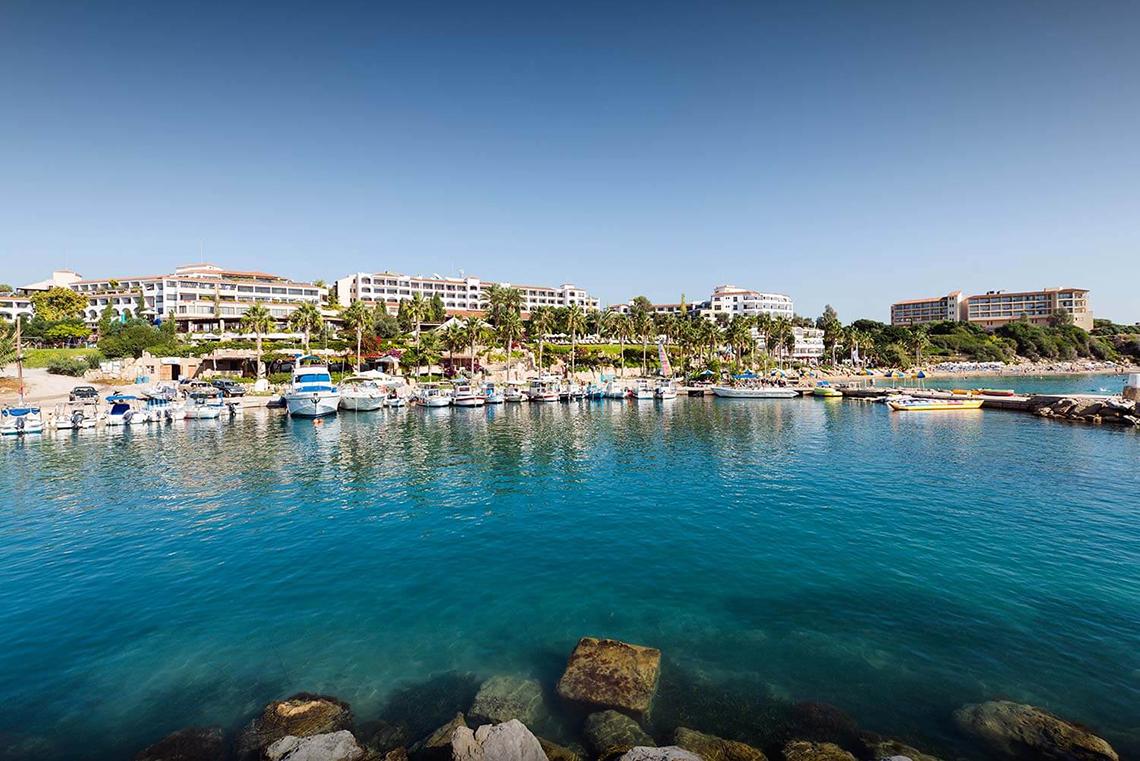 Blick auf die Marina mit vielen geparkten Booten und dem Coral Beach Hotel & Resorts im Hintergrund.