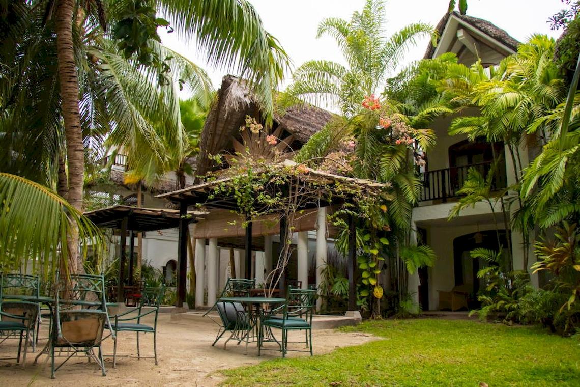 Außenbereich des Village du Pecheur Hotels mit grünen Stühlen und Tischen.