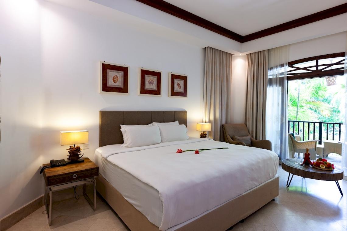 Hotelzimmer im Village du Pecheur mit einem großen Bett, Balkon und Blick auf die Außenterrasse.