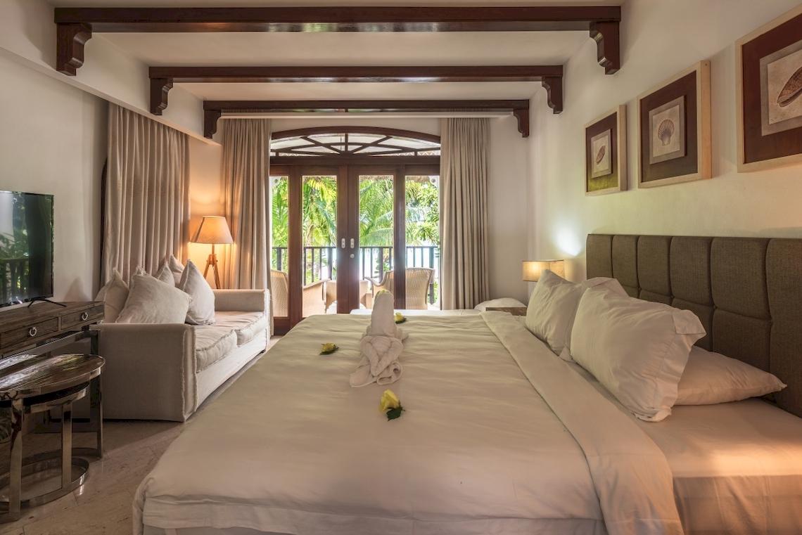 Schlafzimmer im Village du Pecheur Hotel mit einem großen Bett, Couch, Fernseher und Balkon