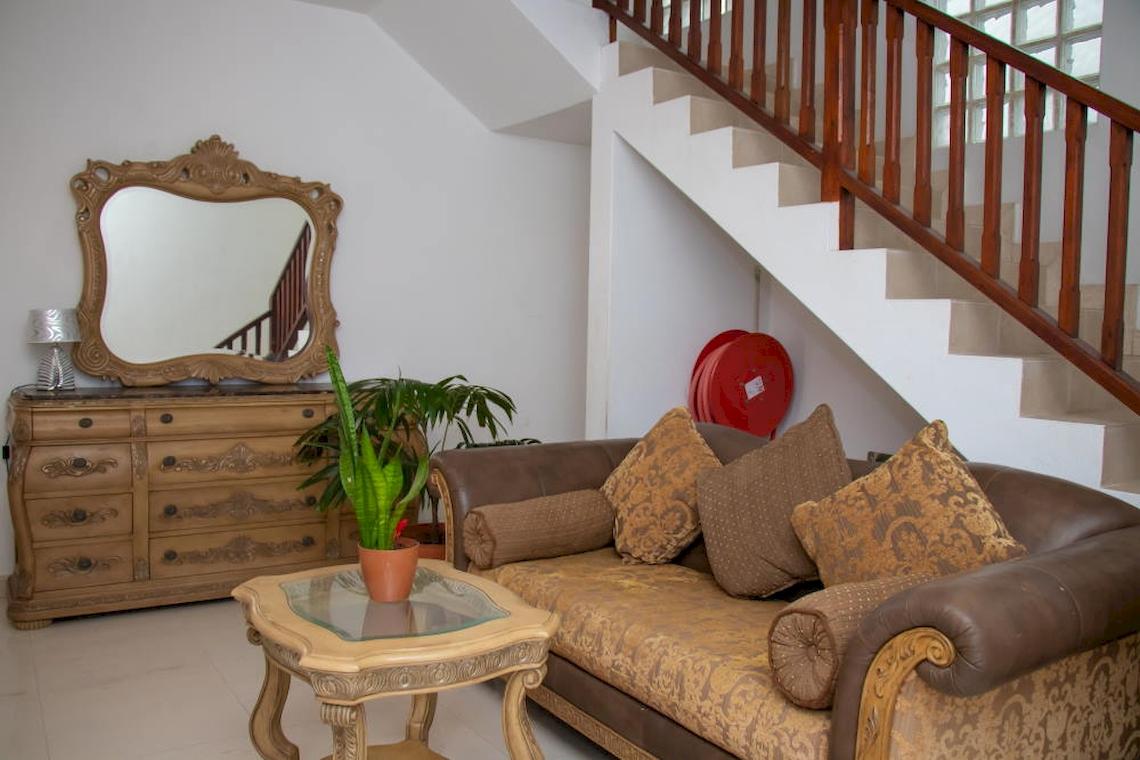 Wohnzimmer des Village du Pecheur Hotels mit Sofa, Tisch, Spiegel und Treppe.