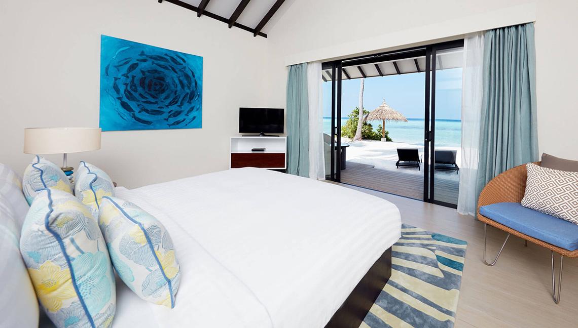 Schlafzimmer im Amari Havodda Maldives Hotel mit Blick auf den Strand und das Meer.