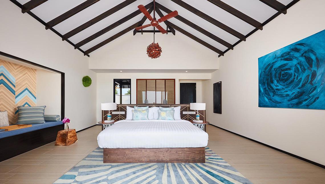 Schlafzimmer im Amari Havodda Maldives mit großem Bett, Dekor und Deckenventilator.