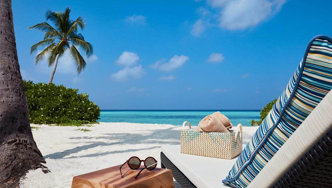 Strand am Amari Havodda Maldives mit Lounge-Bereich, Sonnenbrille und Korb